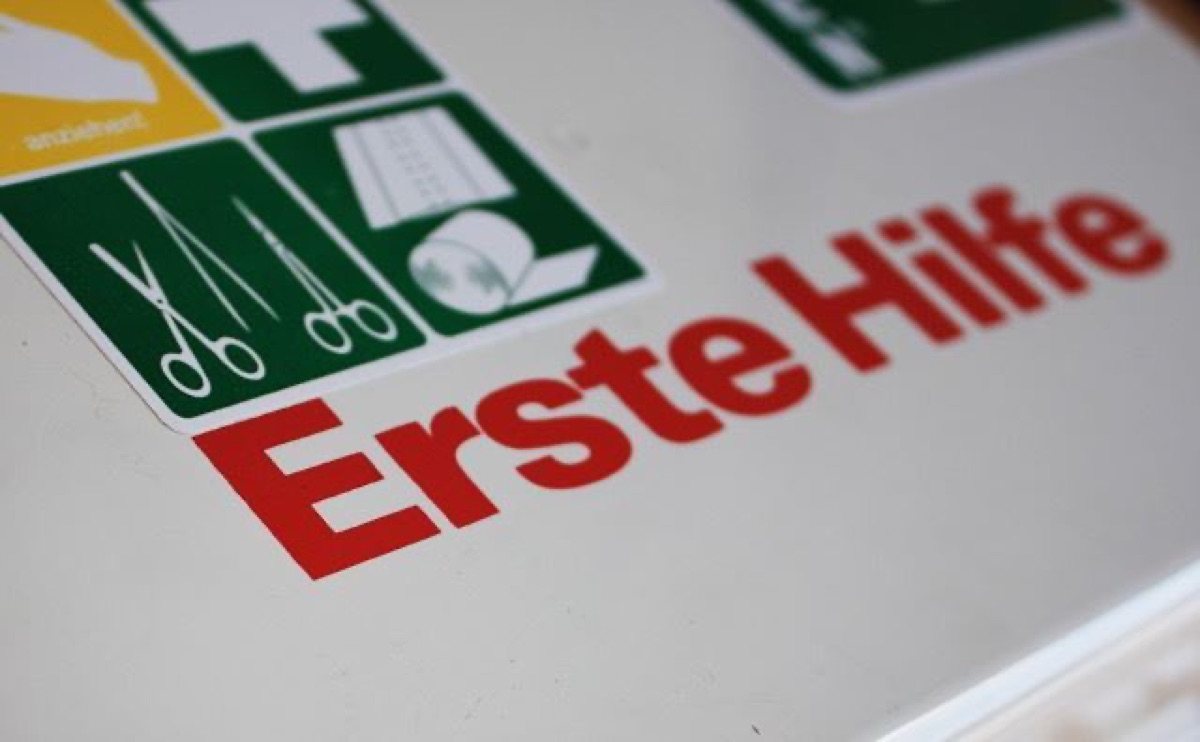 Erste-Hilfe-Schild mit Verbandssymbolen